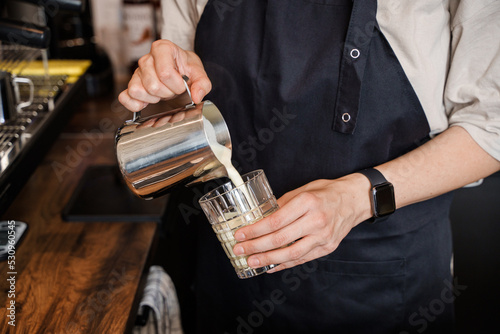 Shot of elderly lady coffee maker pouring milk to cup in coffee bar.