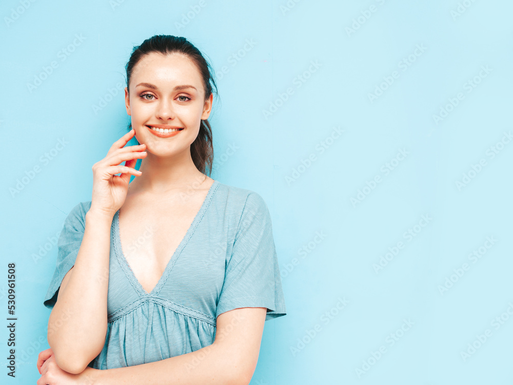 Portrait of young beautiful smiling female in trendy summer dress. Sexy carefree woman posing near blue wall in studio. Positive model having fun and going crazy. Cheerful and happy Portrait of young beautiful smiling female in trendy summer dress. Sexy carefree woman posing near blue wall in studio. Positive model having fun and going crazy. Cheerful and happy