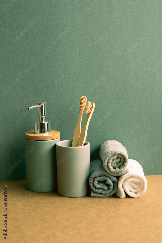 Soap, shampoo bottle and cotton towels, toothbrush on brown shelf. green wall background. bathroom interior