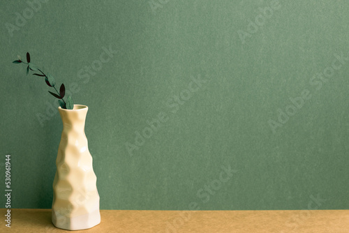 Vase of eucalyptus leaf on brown table. green wall background. retro style home interior