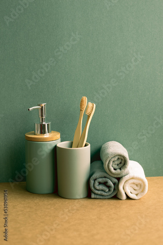 Obraz na płótnie Soap, shampoo bottle and cotton towels, toothbrush on brown shelf. green wall background. bathroom interior w salonie