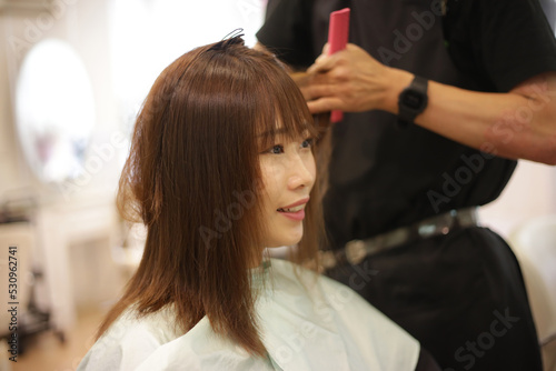女性の髪を切る男性美容師