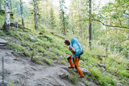 A person climbs uphill on a trail with a large backpack on sleep, hiking alone, mountain climbing, hiking, forest walk