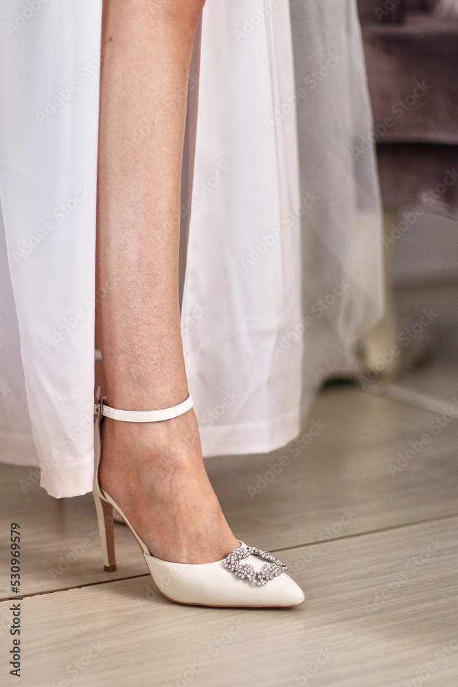 Legs of a girl in white, stylish high-heeled shoes. Legs of a girl in white, stylish high-heeled shoes.