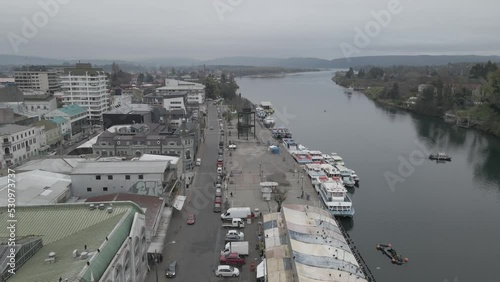 Push in aerial view of the Costanera in Valdivia City with people, commerce, cars and boats photo