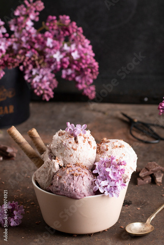 Tasty Lilac purple homemade ice cream frozen dessert in a beige bowl with two wafer straws on rustically background. photo