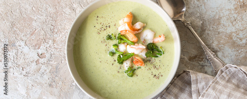 a bowl of creamy broccoli soup with shrimp on a light table
