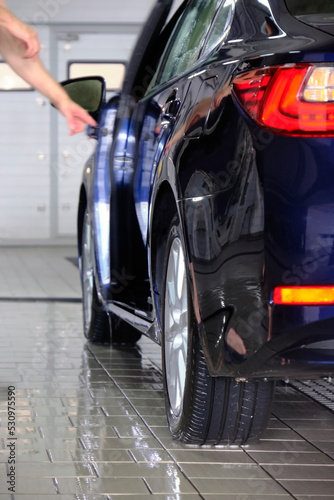 wet shiny car during a hand wash at a cleaning station, shallow depth of field, focus on the rear bumper
