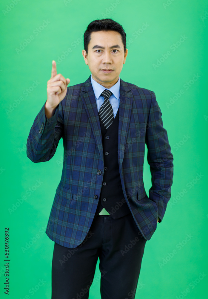 Millennial Asian smart handsome cheerful proud successful professional male businessman ceo entrepreneur in plaid formal suit and necktie standing smiling posing on green background. Millennial Asian smart handsome cheerful proud successful professional male businessman ceo entrepreneur in plaid formal suit and necktie standing smiling posing on green background.