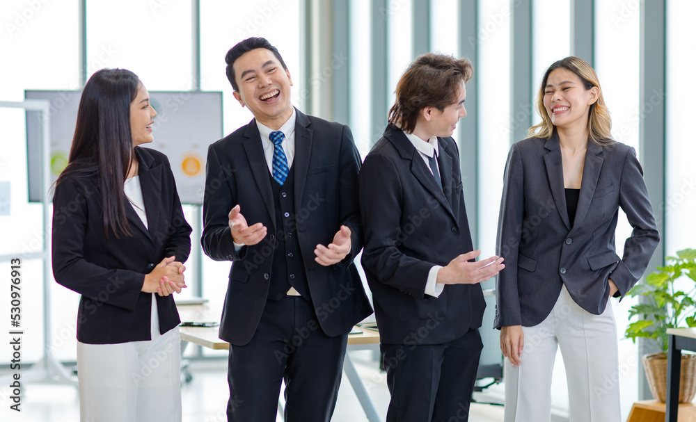 Millennial Asian successful professional male businessmen and female businesswomen colleagues standing side by side smiling laughing posing gesturing together in company office meeting room. Millennial Asian successful professional male businessmen and female businesswomen colleagues standing side by side smiling laughing posing gesturing together in company office meeting room.