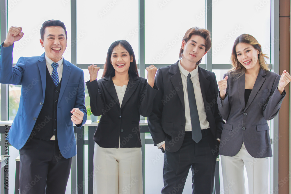 Millennial Asian successful professional male businessmen and female businesswomen colleagues standing side by side smiling laughing posing gesturing together in company office meeting room. Millennial Asian successful professional male businessmen and female businesswomen colleagues standing side by side smiling laughing posing gesturing together in company office meeting room.