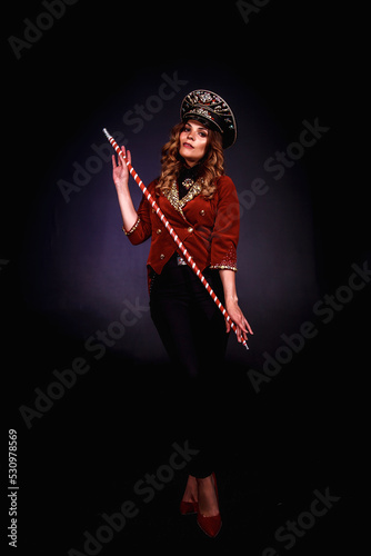 Female magician illusionist of circus with cane showing soap bubbles show at black background. Concept of theatre performance. Woman actress in theatrical clothes with stylish hat in stage costume