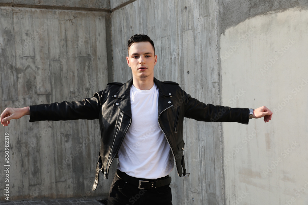 Outdoor portrait of handsome stylish hipster young man wearing leather jacket.