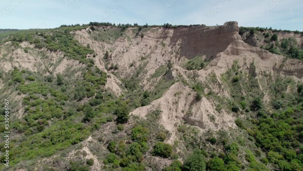 going by drone towards a mountain that is partly green and partly arid going by drone towards a mountain that is partly green and partly arid