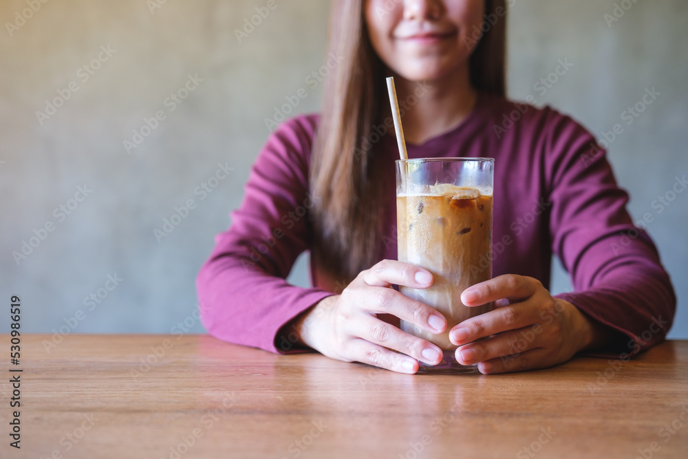 Closeup image of a young woman holding and drinking iced coffee Closeup image of a young woman holding and drinking iced coffee