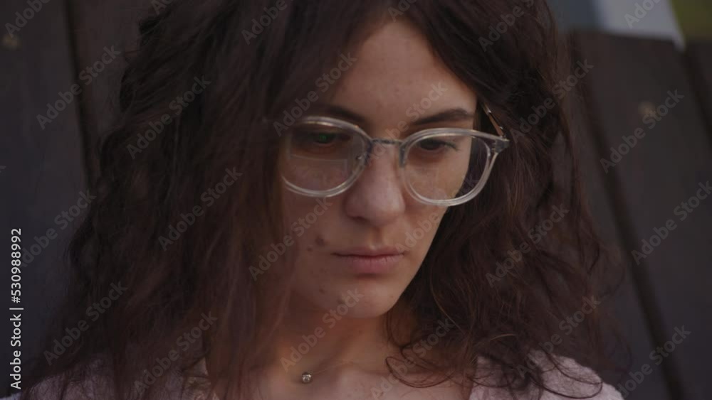 Handheld close up of a curly caucasian woman looking at the laptop reflection in her glasses