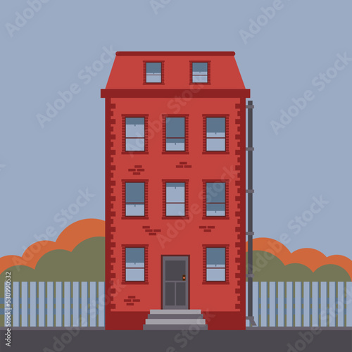 Detailed brick red high-rise house in New York style in autumn against the backdrop of multi-colored bushes and a fence