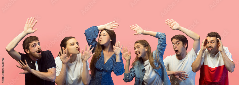 Group of young different people, emotional men and girls face the transparent glass isolated on pink background. Sales, human rights, social gathering, ad