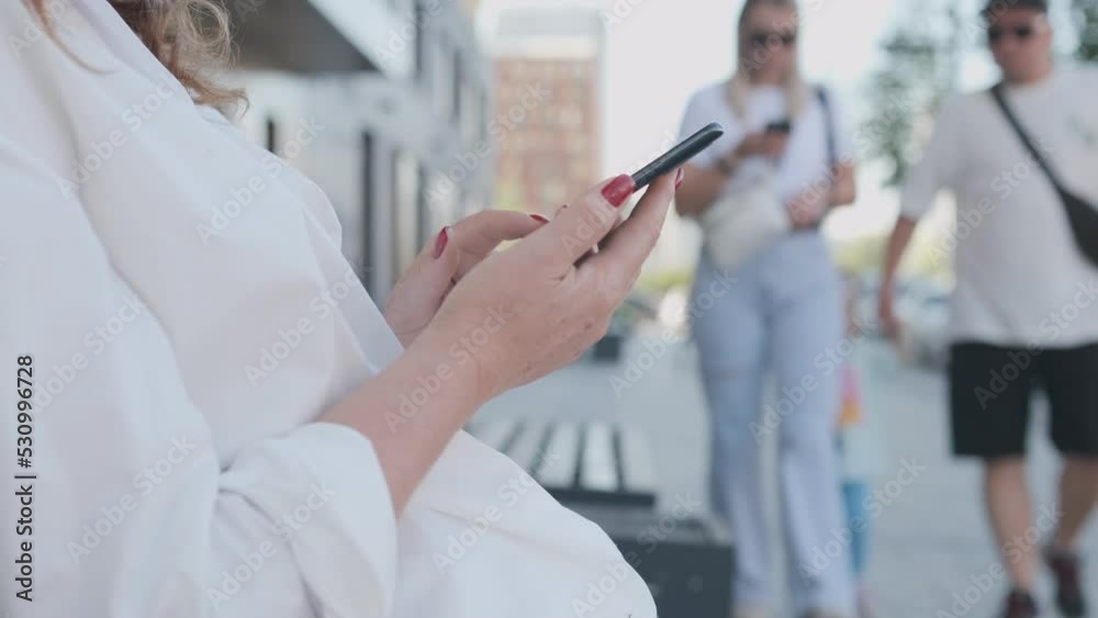 Happy young business woman walking in city street looking into mobile phone smartphone screen chatting online in net smiling answering message in social media using gadget device Happy young business woman walking in city street looking into mobile phone smartphone screen chatting online in net smiling answering message in social media using gadget device