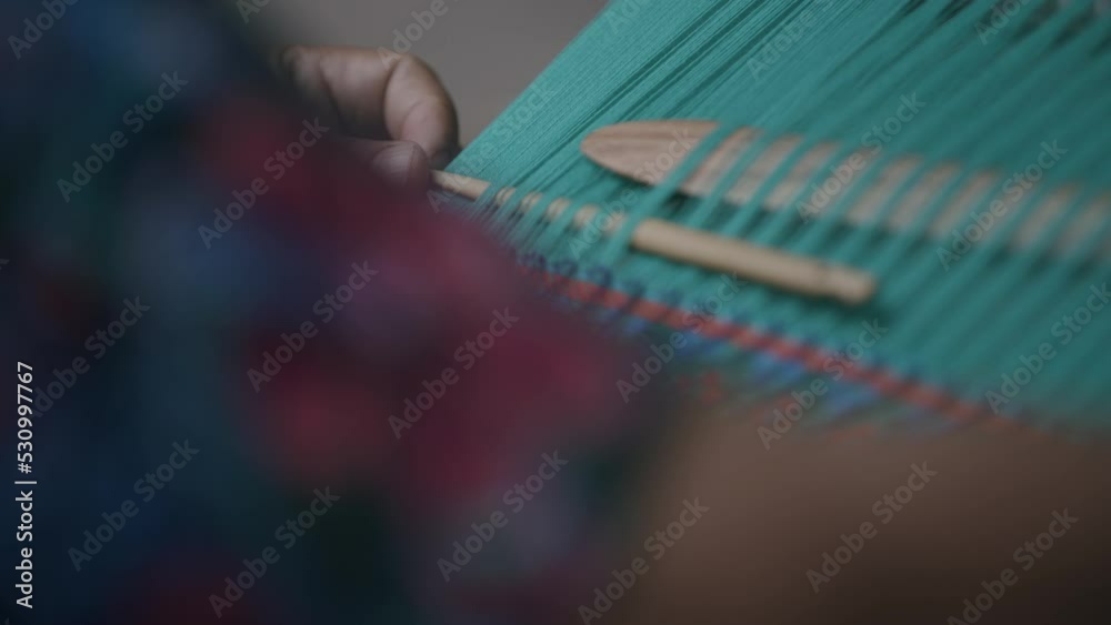 Slow motion as a woman slides a wooden slider down through a fabric in Guatemala as she is making indigenous textiles.