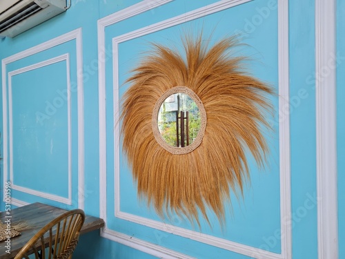 wall decoration in the form of a mirror decorated with straw or rayung.  room decoration and interior design photo