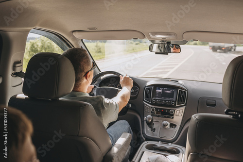 Young man holding steering wheel while driving car. Road trip. Local travel concept. Thirst for adventure.
