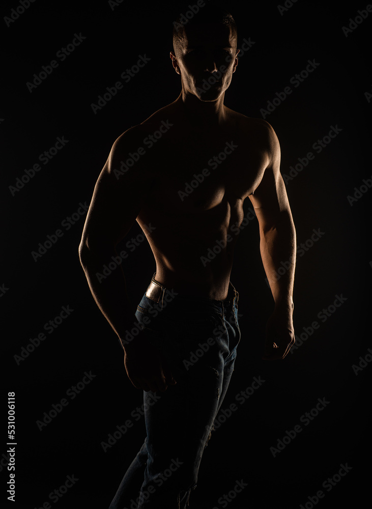 Silhouette of topless guy posing in studio while standing and holding his posture