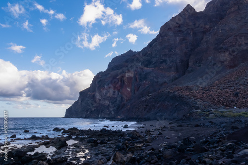 Scenic early morning view on the volcanic sand beach Playa del Ingles in Valle Gran Rey, La Gomera, Canary Islands, Spain, Europe. Massive cliffs of the La Mercia range. moody atmosphere at seaside photo