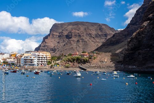Scenic view on the small port of Vueltas seen from Playa de Vueltas in Valle Gran Rey on La Gomera, Canary Islands, Spain, Europe. Small boats are floating in the blue lagoon. Tourist village in back © Chris