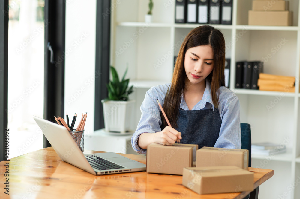 Asian woman hand using laptop, smartphone and tablet and writing notebook at office of her business online shopping. In home Asian woman hand using laptop, smartphone and tablet and writing notebook at office of her business online shopping. In home