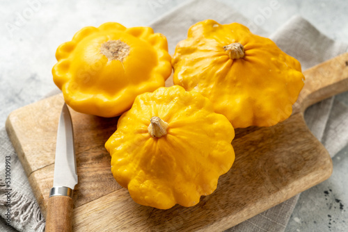 Yellow patisson in a basket on a light gray kitchen table close-up. Autumn harvest of bush pumpkin on a culinary background