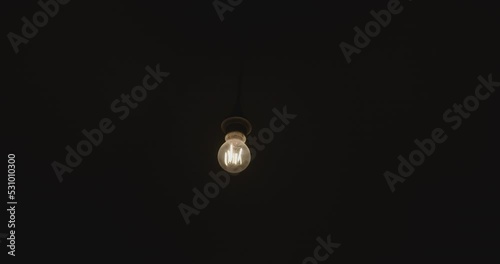 Wallpaper Mural Turn on light bulb slowly swings on the wire. the incandescent lamp is shining in the dark. Slow motion
 Torontodigital.ca