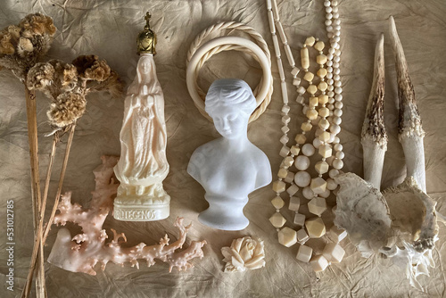 女性の古い白色の彫刻と幾何学のネックレス、鹿の角、珊瑚、皮革を背景にしたアイボリーの標本と植物の集合写真
