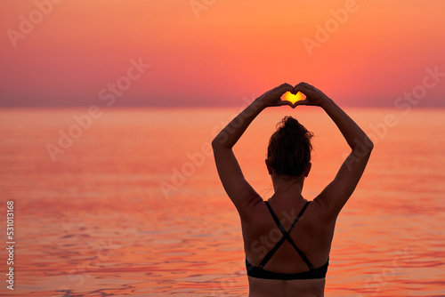 Young woman swimming in the sea on sunrise