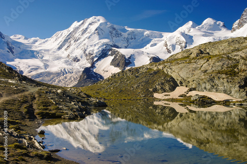 Famous Lyskamm ('People Eater') mountain mirrored in ripple water of Riffelsee lake, Swiss Alps, Valais, Switzerland. Pair of twin peaks Castor and Pollux on the right