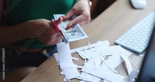 Woman counterfeiter cuts dollar bills with scissors at work table closeup