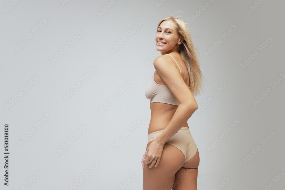 Fototapeta premium Beautiful young woman isolated on light background. Caring for women's health, body treatment, sport and natural beauty concept. Back view
