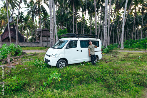 tourist with white camper van parked in a green field surrounded by trees in Bali Indonesia © Alexander White
