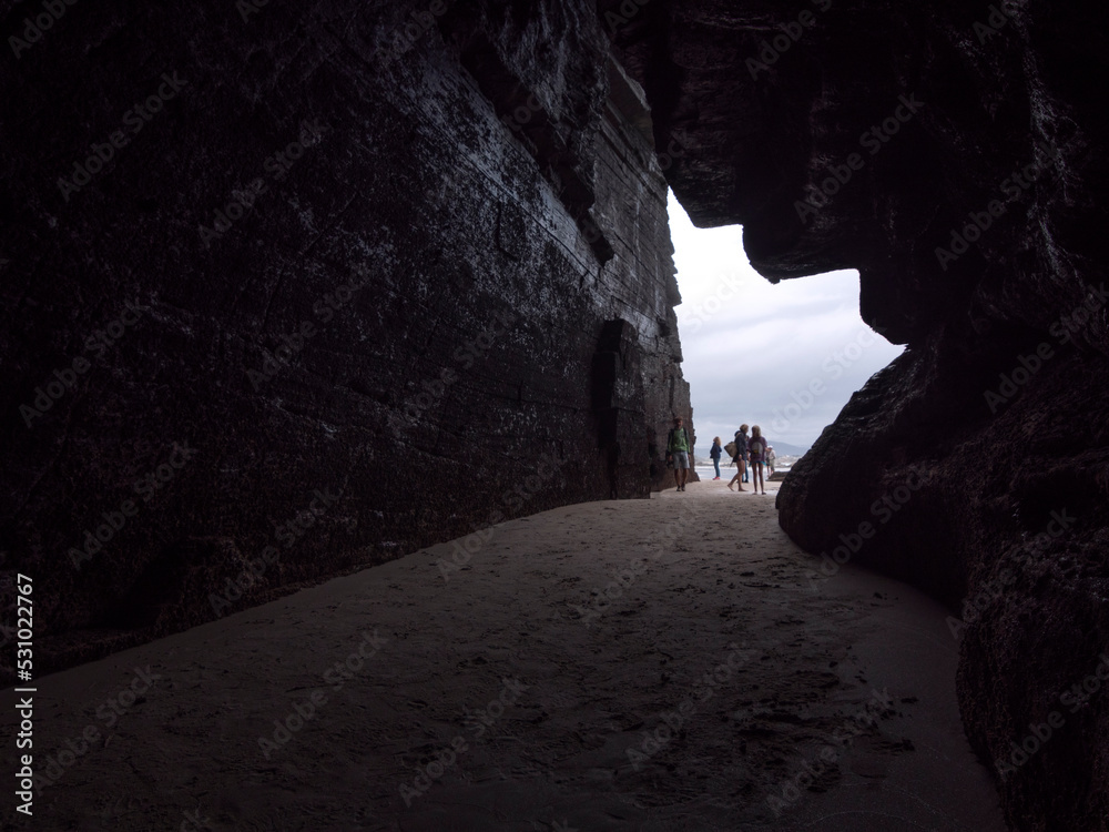 Horizontal view of tourists entering a beach cave in low tide.