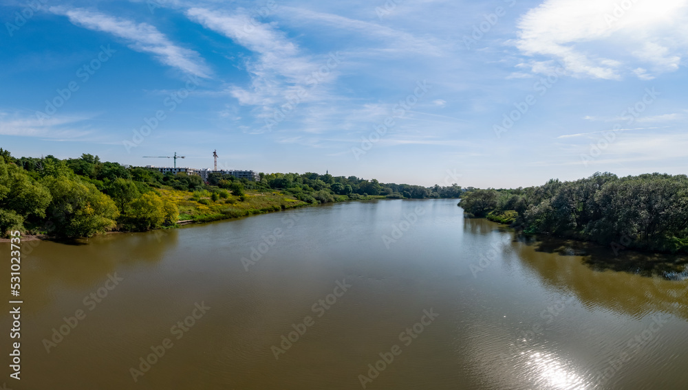 Rzeka Odra, w tle lekko pochmurna pogoda, błękit nieba zieleń przy brzegu, pora letnia, Odra w odcinku województwa Opolskiego
