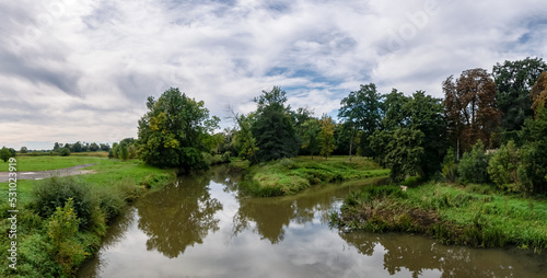 krajobraz rzeki Osob  ogi w zachodniej Polsce w jasnych zielono niebieskich barwach i lekko pochmurnej pogodzie