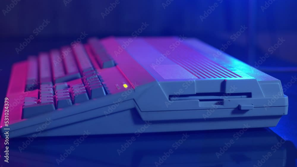 Side view of a hand inserting a floppy into a microcomputer and loading the disk in a dark atmosphere