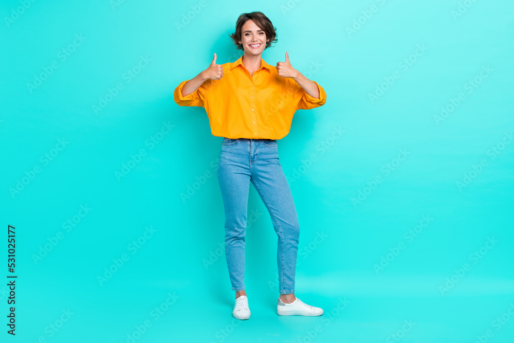 Full length photo of cheerful pretty lady stand empty space arm demonstrate yes quality symbol isolated on cyan color background Full length photo of cheerful pretty lady stand empty space arm demonstrate yes quality symbol isolated on cyan color background