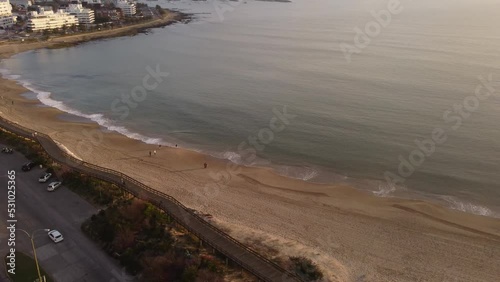 Wallpaper Mural People walk at sunset along Punta del Este beach with city in background, Uruguay. Aerial panoramic view Torontodigital.ca