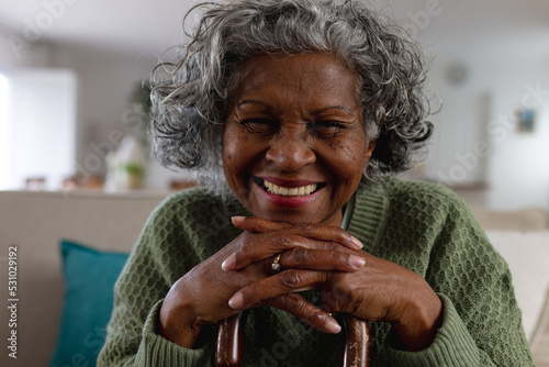 Happy senior african american women with cane siting alone in the sunny living room