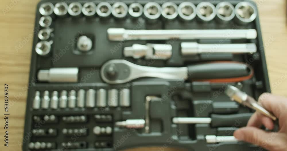 Auto mechanic connects a metal extension to a small ratchet wrench, adds a bit. Demonstration of the work of the key, a set of tools on the background, close-up, top view Auto mechanic connects a metal extension to a small ratchet wrench, adds a bit. Demonstration of the work of the key, a set of tools on the background, close-up, top view