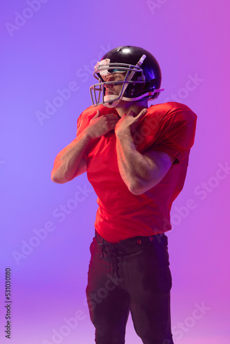 Caucasian male american football player wearing helmet with neon blue and purple lighting © wavebreak3