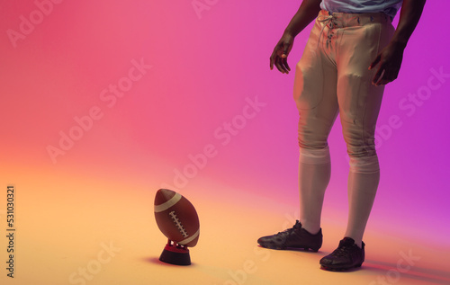 Midsection of african american male american football player with neon pink lighting