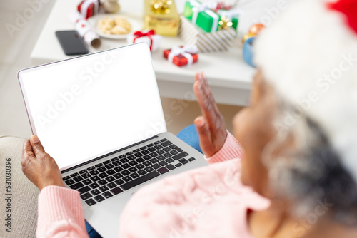 Happy senior african american women wearing santa claus hat and holding laptop with copy space