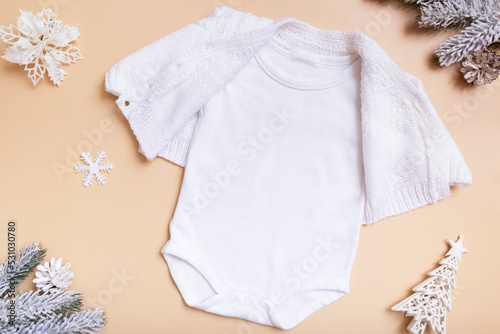 White baby bodysuit mockup for logo, text or design on beige background with winter decotations top view photo